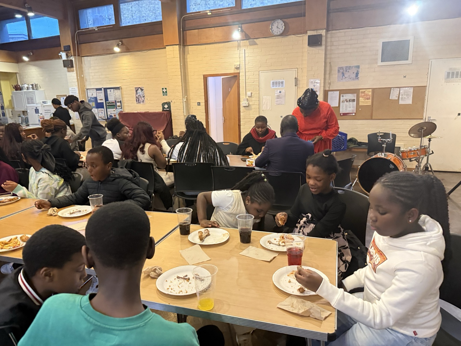Young people eating together around tables after a service